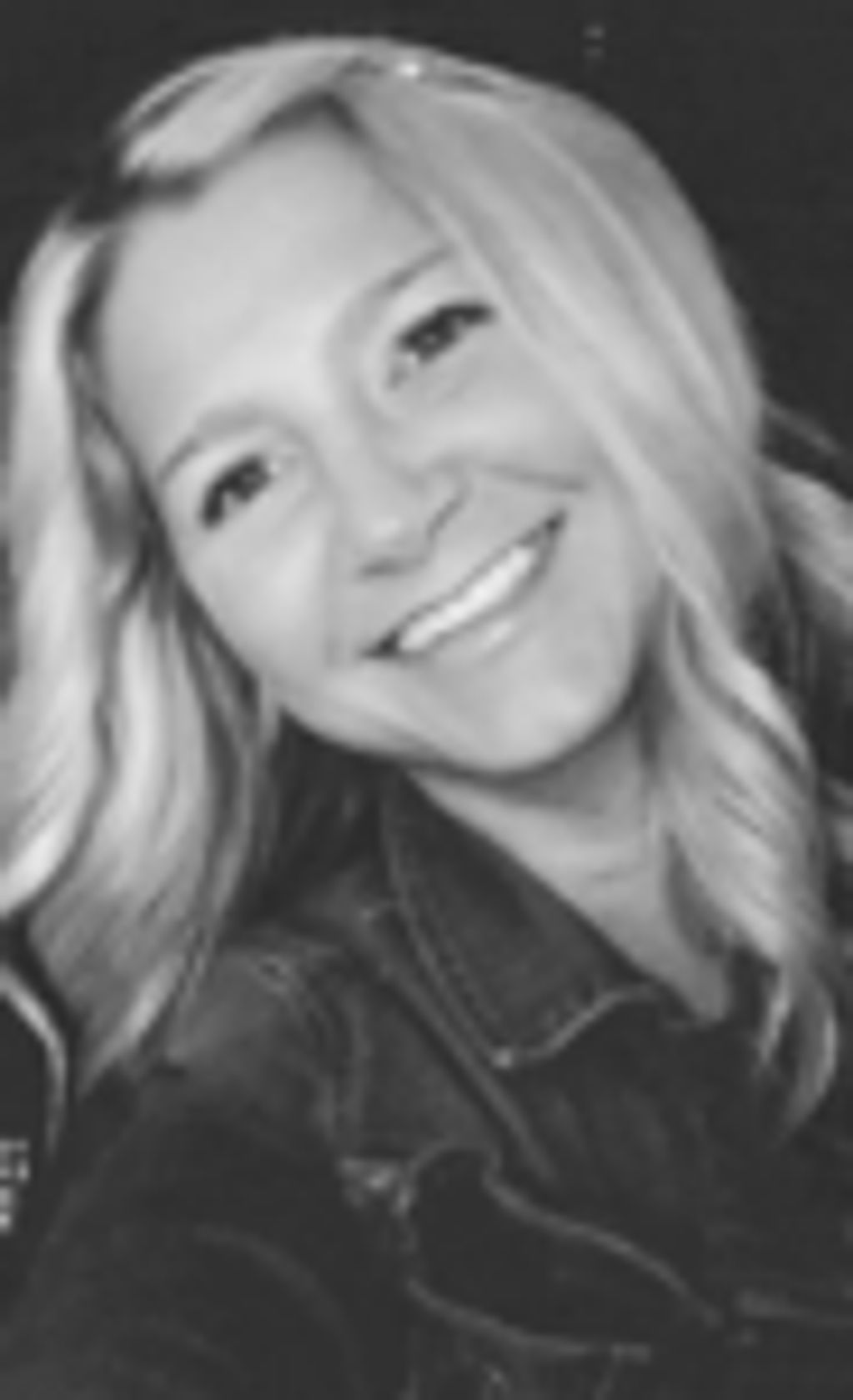 Blonde woman smiling in a black-and-white photo.
