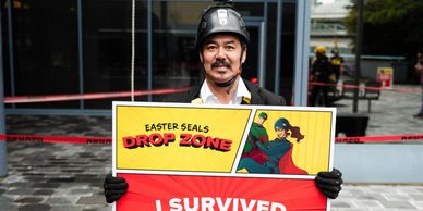 Man holding an Easter Seals Drop Zone survivor sign.