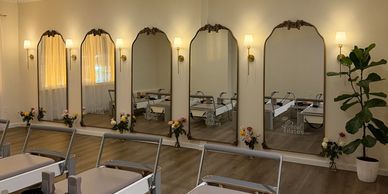 Elegant Pilates studio with reformer machines and decorative mirrors.