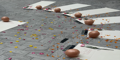 Pilates mats with roses and decorative balls on a gray tiled floor scattered with petals.