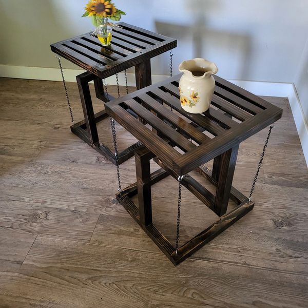 Two wooden hanging side tables with decorative vases on top.