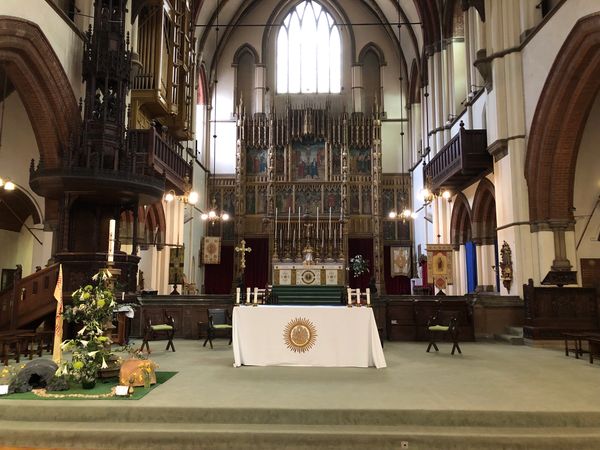 Interior of a historic church altar with intricate woodwork and stained glass windows.