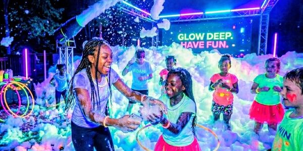 OkChildren enjoying a glowing foam party with bright lights.