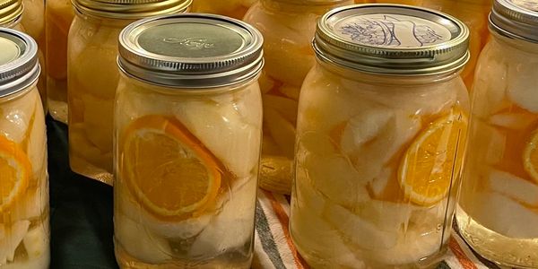 Glass jars filled with preserved fruit slices and liquid.