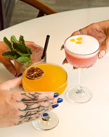Three diverse cocktails with garnishes and styled nails.