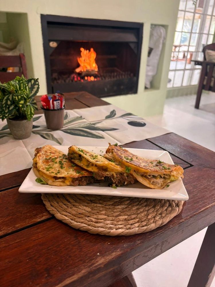Grilled quesadillas served on a white plate with a cozy fireplace in the background.