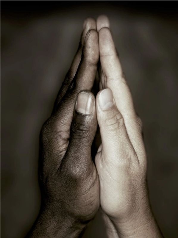Two hands with different skin tones pressed together symbolizing unity.
