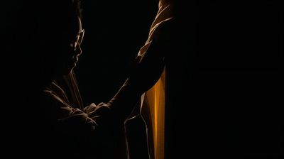 Silhouetted figures in a dimly lit, intimate moment.