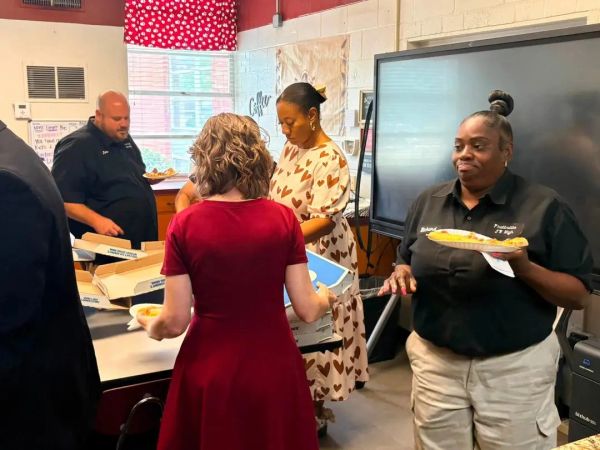 People serving and receiving food in a room.