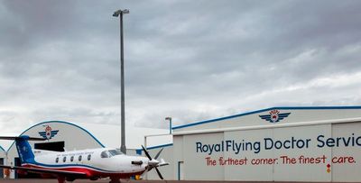 A Royal Flying Doctor Service plane parked outside their hangars on a cloudy day.