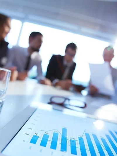 Business meeting with focus on a financial graph on a tablet.