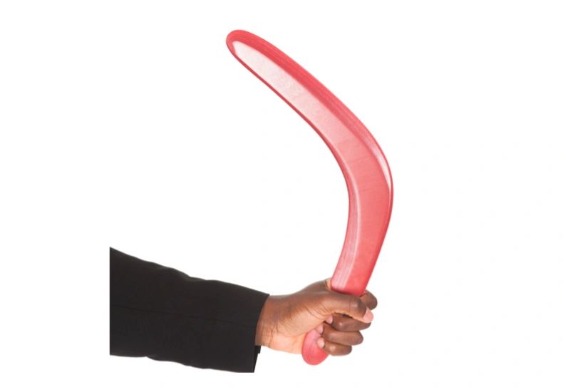 Hand holding a red boomerang against a white background.