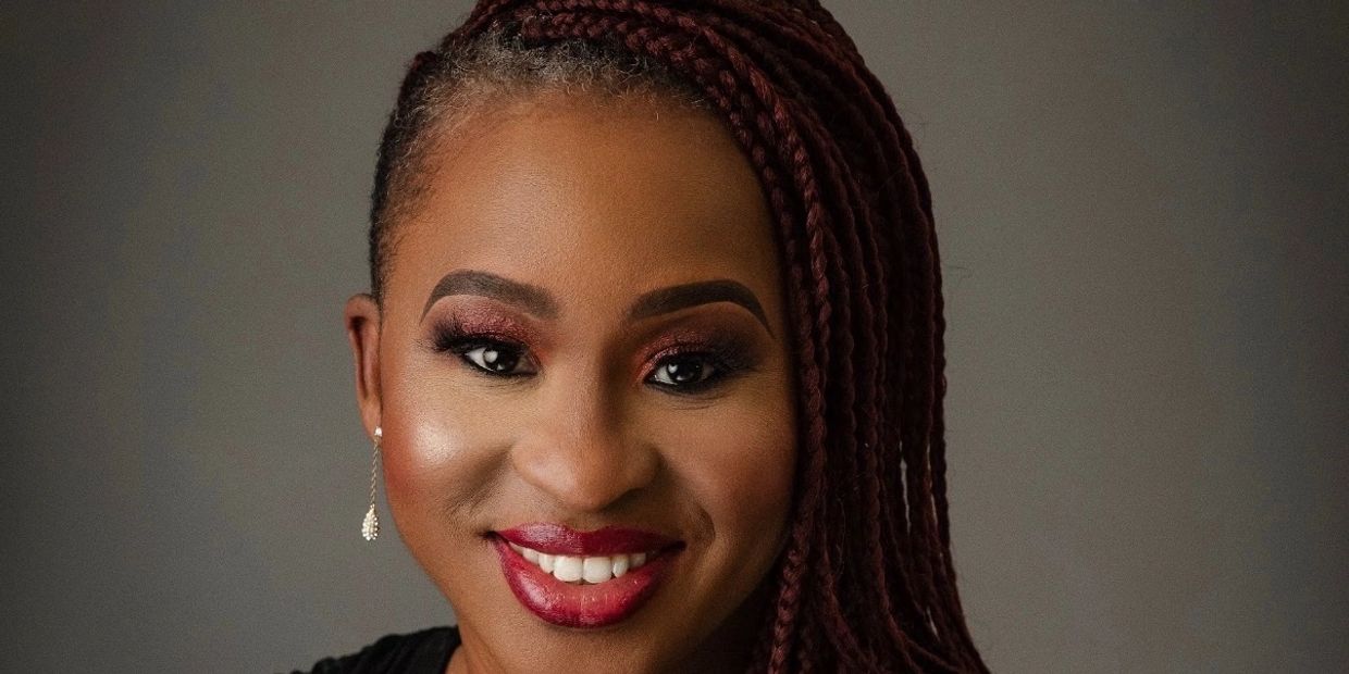 Close-up portrait of a smiling woman with braided hair and elegant makeup.