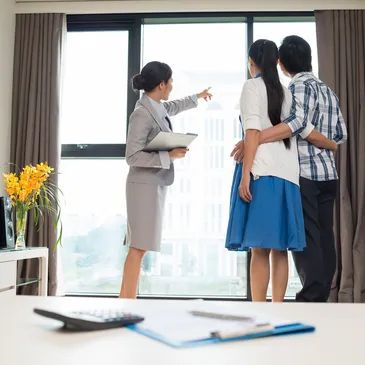Real estate agent showing a couple a city view from an apartment window.