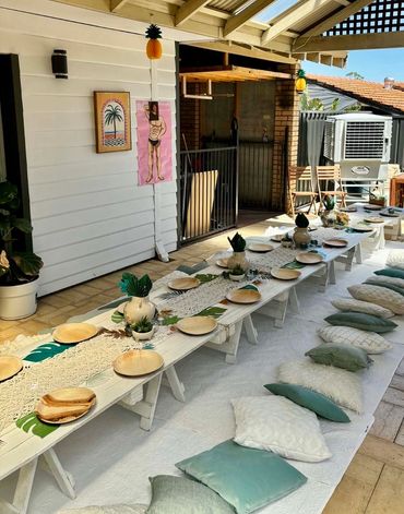 Outdoor dining setup with low tables, cushions, and tropical decorations.