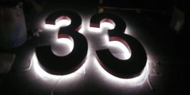 Illuminated number 33 sign glowing in the dark.