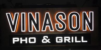 Illuminated restaurant sign reading 'VINASON PHO &amp; GRILL' at night.