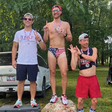 Three men posing with medals and peace signs outdoors.