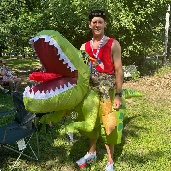 Man in dinosaur costume outdoors.
