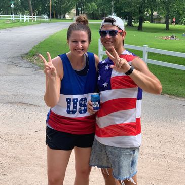 Two people in patriotic USA outfits showing peace signs.