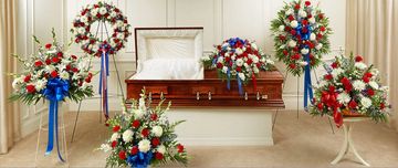 Coffin with patriotic floral arrangements in red, white, and blue.