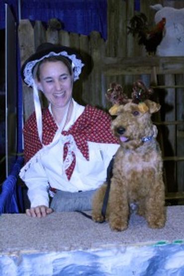 Woman in period costume with a dog wearing reindeer antlers.