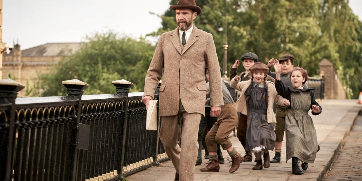 Man in vintage suit walking with children following.