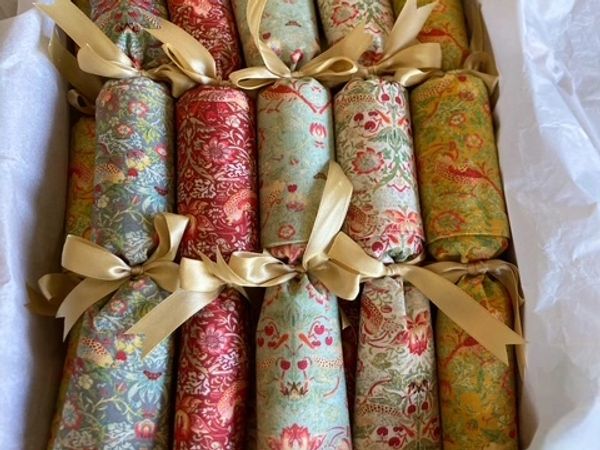 A box of colorful fabric rolls tied with golden ribbons, arranged neatly.