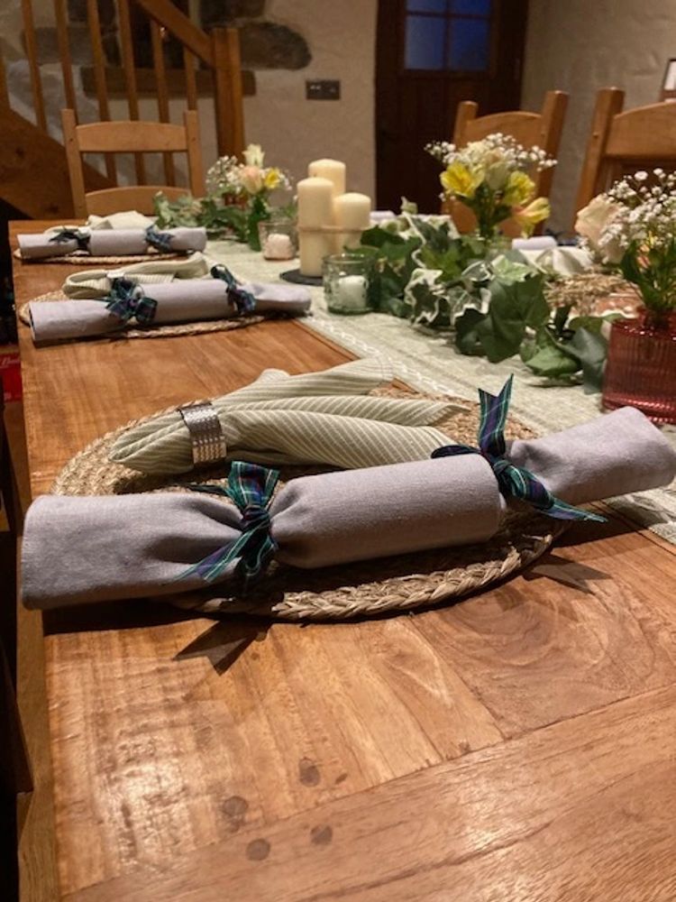 Rustic dining table set with cloth napkins, candles, and floral centerpieces.