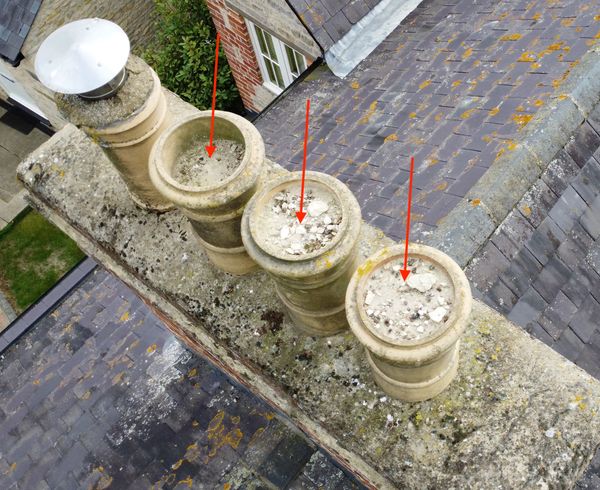 Four stone chimney pots with debris inside.