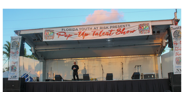 wide view of covered mobile stage with large “Pop-Up Talent Show” banner and side branding