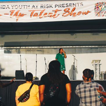 artist performing on a mobile stage under a large event banner with audience in front