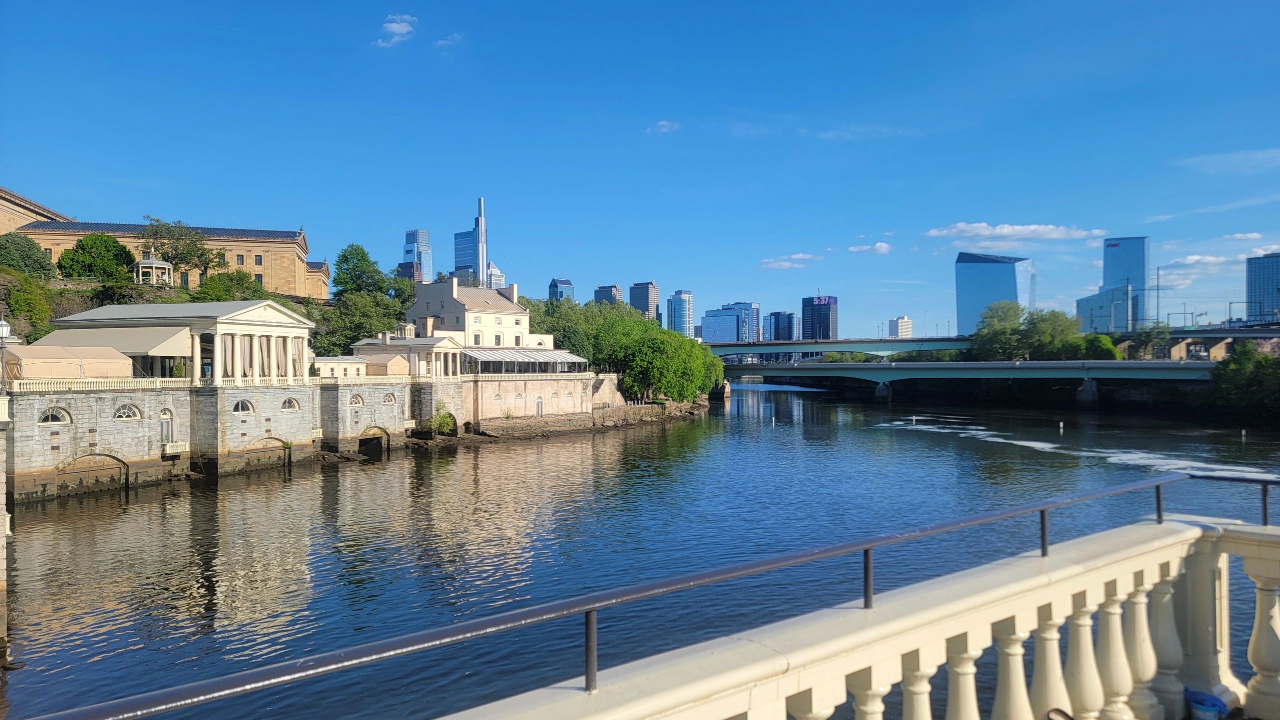 Clear blue sky over a river with city skyline and historic buildings.