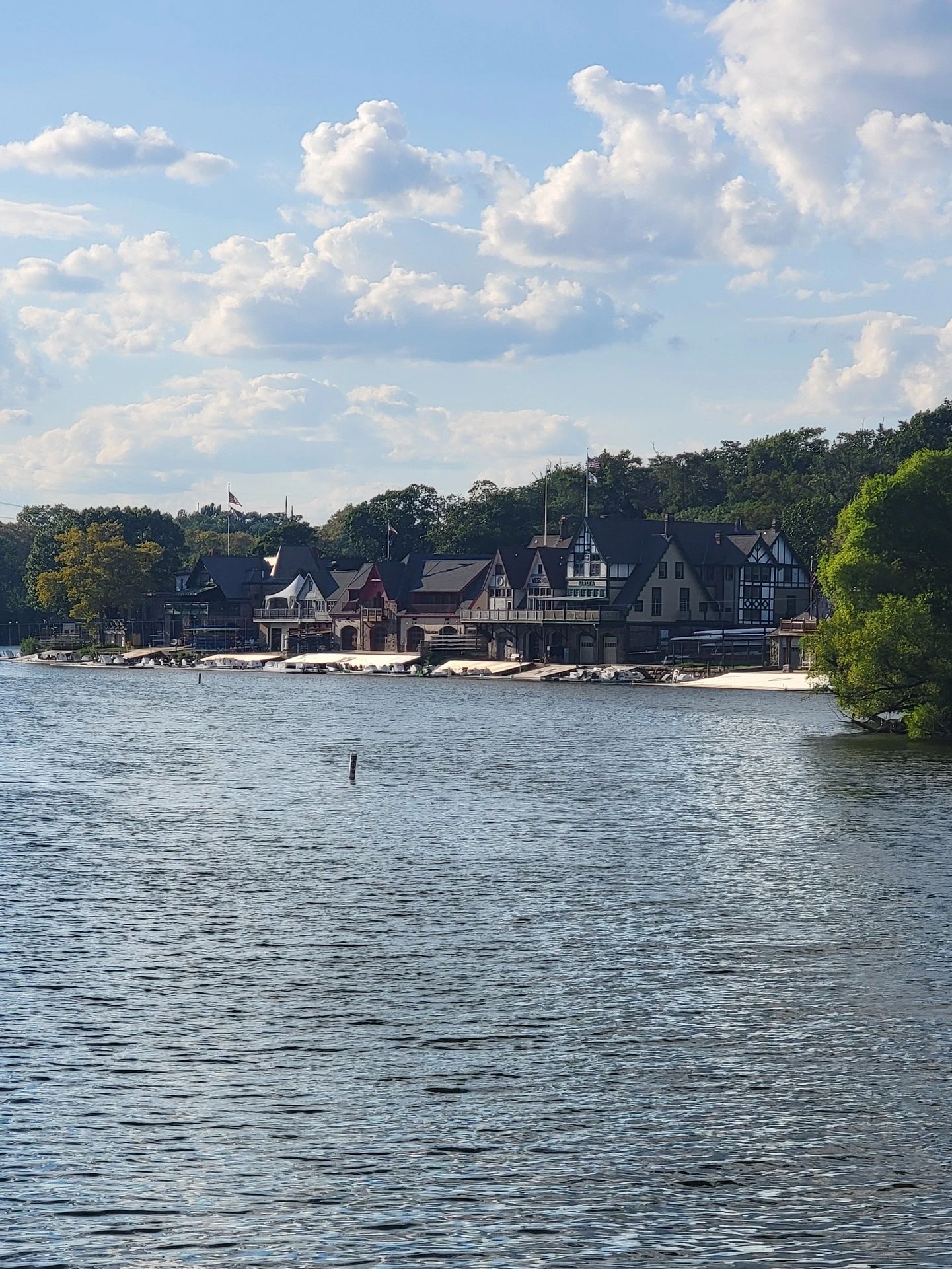 Scenic view of lakeside boathouses under a partly cloudy sky.
