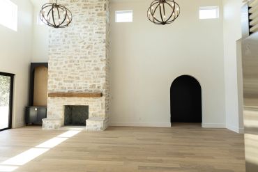 Bright living room with stone fireplace and wooden floors.