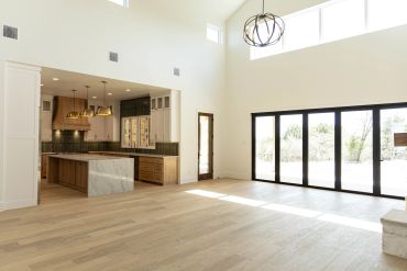 Bright and spacious modern kitchen with large windows and wooden flooring.