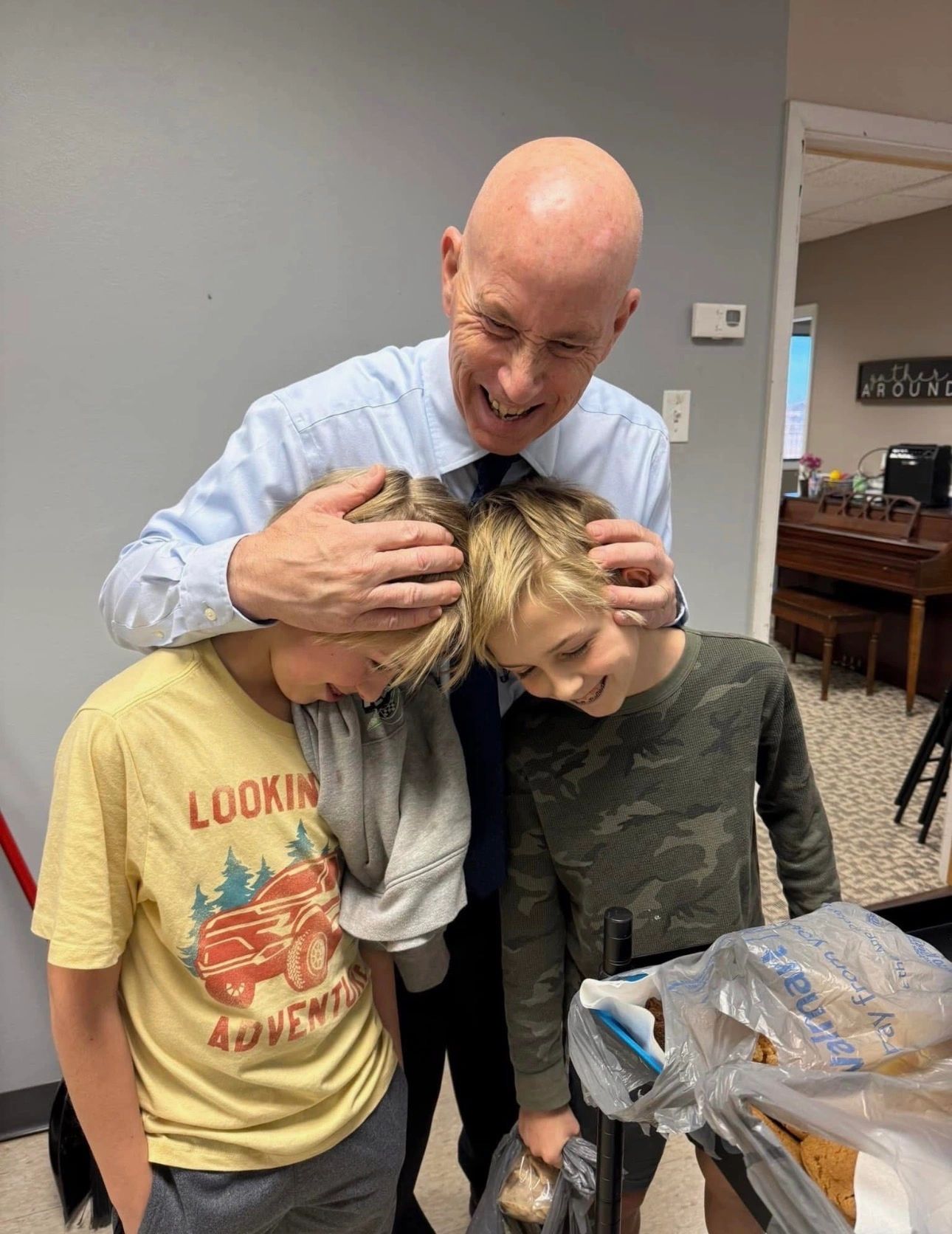 Man affectionately hugging two smiling boys.