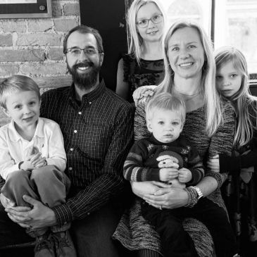 Black and white family portrait with smiling parents and children.