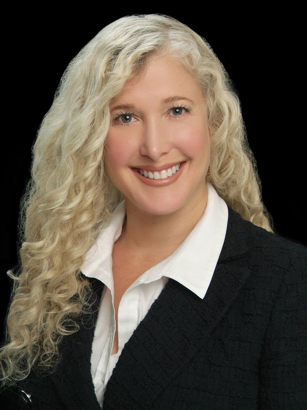 Professional woman with curly blonde hair smiling.