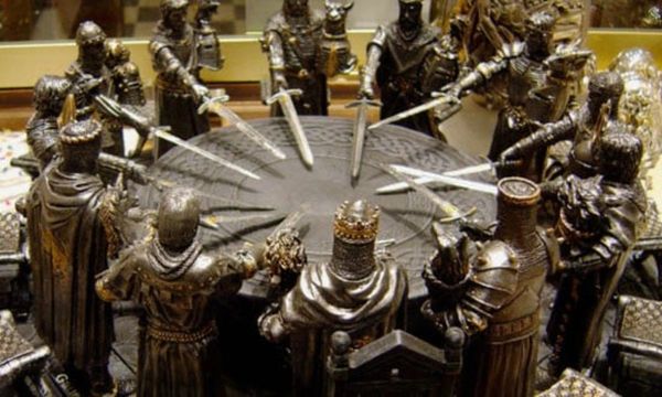 Bronze statues of knights around a circular table with swords.