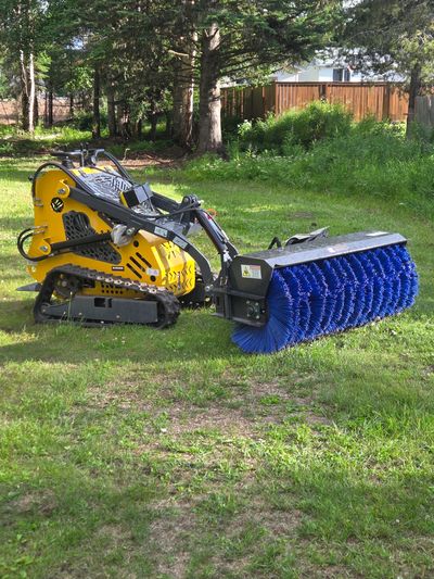 Yellow tracked vehicle with large blue brush attachment.
