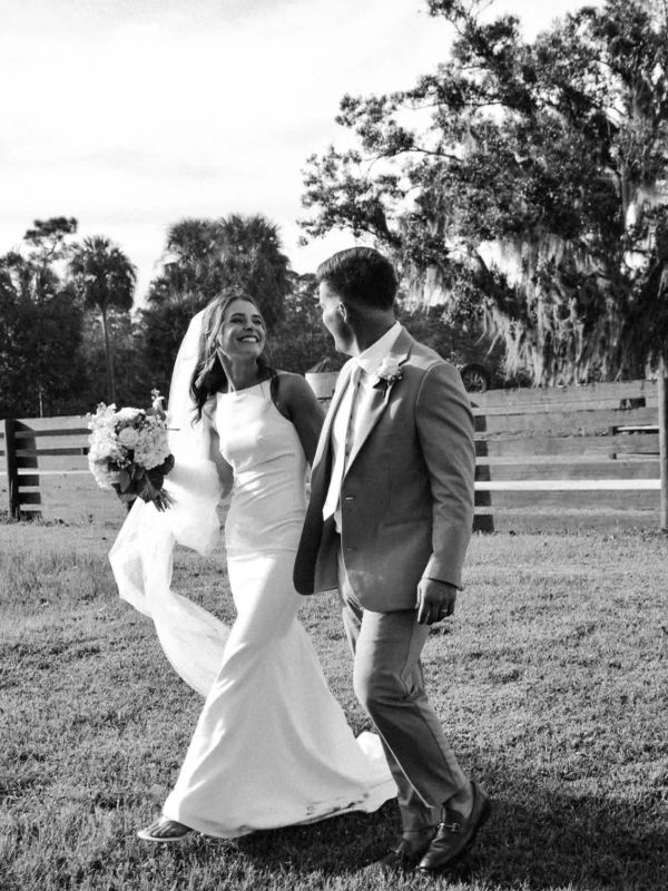 Bride and groom walking outdoors, smiling at each other.