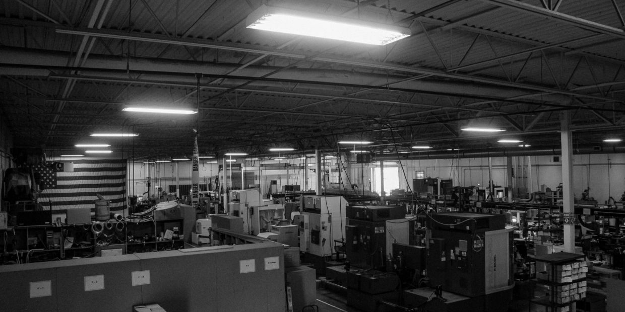 Black and white image of a spacious industrial workshop filled with machines and equipment.