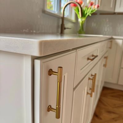 Close-up of a white kitchen cabinet with brass handles.
