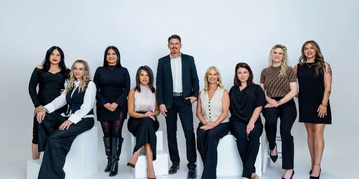 A group of nine professionals in formal attire posing against a white background.