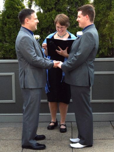A photograph of two grooms at a wedding, with an officiant.