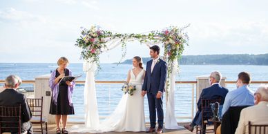 A photograph of a bride and a groom at a wedding, with an officiant.