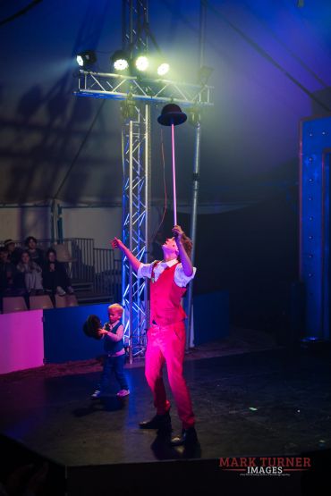 Performer balancing a hat on a stick in a circus.