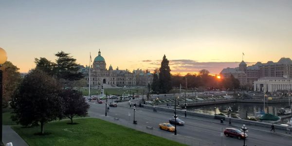Sunset over a city with historic buildings and a waterfront.