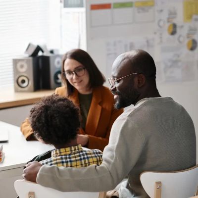 Child and father in a meeting with a female professional.